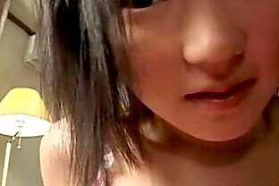 An Asian girl is sitting on the edge of a bed. The c from